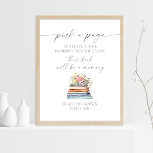 May include: A white sign with a brown frame, featuring the text "pick a page and leave a note or simply sign your name this book will be a memory of all the guests who came". The sign is decorated with a watercolor illustration of a stack of books with flowers on top.