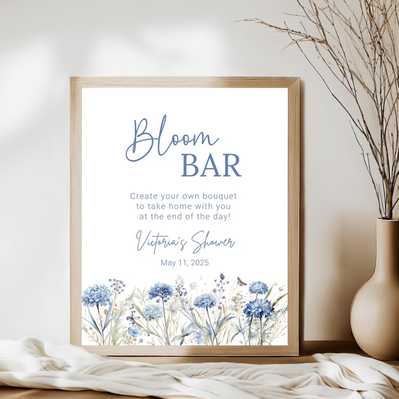Op de afbeelding: Een bord voor een "Bloemenbar" op een bruidsdouche. Het bord heeft een aquarel-illustratie van blauwe bloemen en groen. De tekst luidt "Maak je eigen boeket om mee naar huis te nemen aan het einde van de dag! Victoria's Shower 11 mei 2025."
