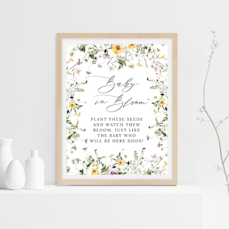 Op de afbeelding: Een printbaar babyshower-bord met een bloemenontwerp en de tekst "Baby in Bloom. Plant deze zaden en bekijk hoe ze bloeien, net als de baby die binnenkort zal komen!"
