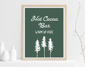 Könnte beinhalten: Gerahmter Druck mit dunkelgrünem Hintergrund und weißem Text mit der Aufschrift "Hot Cocoa Bar, Warm Up Here". Darunter befinden sich drei weiße Kiefernsilhouetten. Der Rahmen ist hellbraun.