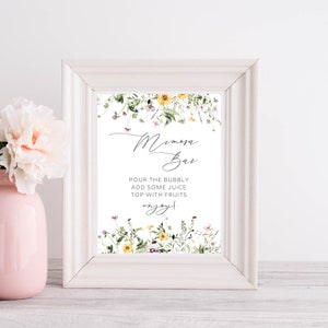 May include: A framed white sign with the words "Mimosa Bar" in elegant script, surrounded by watercolor floral accents. The sign includes instructions: "Pour the bubbly, add some juice, top with fruits, enjoy!"