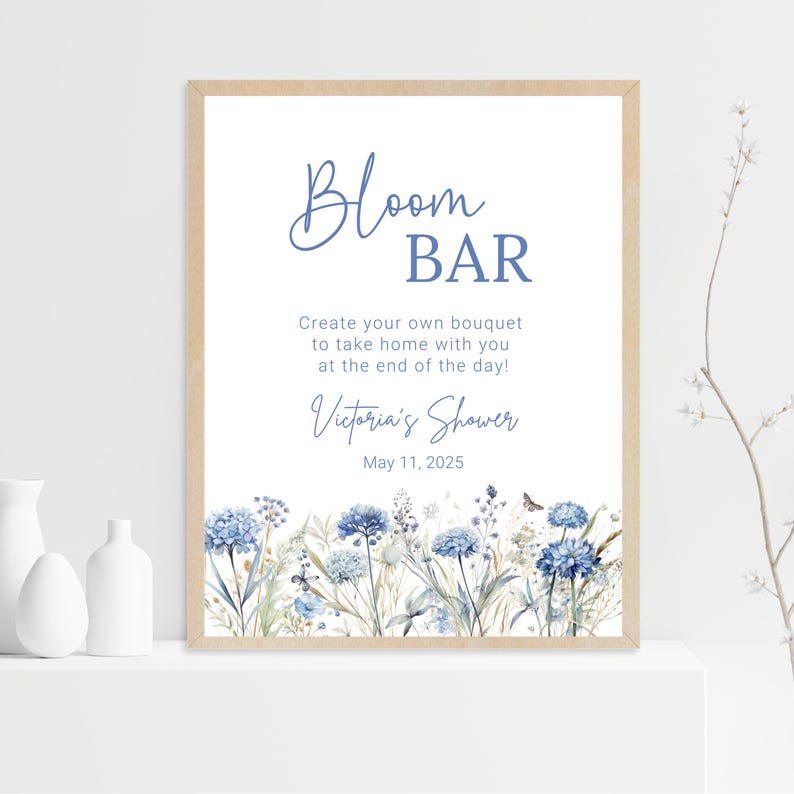 Op de afbeelding: Een wit bord met blauwe tekst en bloemillustraties. Het bord staat "Bloom Bar" en "Maak je eigen boeket om mee naar huis te nemen aan het einde van de dag!" Het staat ook "Victoria's Shower" en "May 11, 2025" erop.
