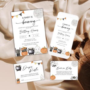 Könnte beinhalten: Ein Babyparty-Einladungsset mit weißem Hintergrund und Aquarellillustrationen von einem Mond, Kürbissen, einem schwarzen Kessel, einem Geist und einer Fledermaus. Der Text lautet A Baby Is Brewing, Diaper Raffle und Books for Baby.