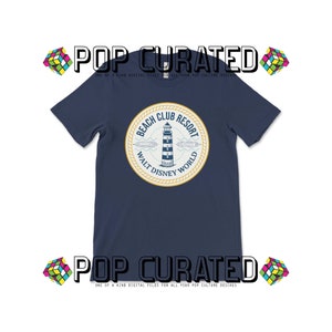 May include: A navy blue t-shirt with a white and yellow circular graphic of a lighthouse with the text "Beach Club Resort Walt Disney World".