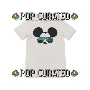 Puede incluir: Camiseta blanca con un gr&aacute;fico de Mickey Mouse con gafas de sol. Las gafas de sol reflejan la atracci&oacute;n Spaceship Earth en Epcot. El texto "POP CURATED" aparece en la parte superior e inferior de la imagen.