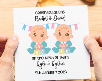May include: A white card with a congratulations message for Rachel & David on the birth of twins Kyle & Kylian on January 5th, 2023. The card features an illustration of two baby boys holding blocks that spell out ABC.