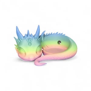 Könnte beinhalten: Eine schlafende Drachenfigur in Pastell-Regenbogenfarben. Der Drache hat einen detaillierten Kopf mit Hörnern und einem stacheligen Rücken. Die Figur liegt mit eingerolltem Schwanz, was einen skurrilen Effekt erzeugt.