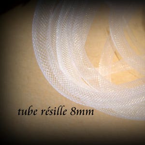 May include: A coiled length of white mesh tubing, 8mm in diameter, is displayed against a light brown background. The text "tube résille 8mm" is visible in the image. The mesh has a woven pattern, and the overall effect is delicate and translucent.