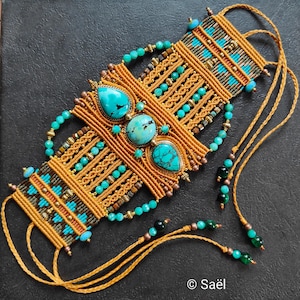 Puede incluir: Pulsera de macramé hecha a mano con tres grandes piedras turquesas y pequeñas cuentas turquesas. La pulsera está hecha con un cordón color beige y cuentas de bronce. El diseño presenta intrincados nudos y patrones geométricos.