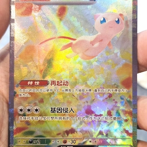 以下が含まれることがあります： ホログラフィックポケモンカード、ミュウEX。カードにはピンク色のミュウのイラスト、日本語のテキスト、HP180が描かれています。カードの背景は光沢があり、さまざまなシンボルとテキストが施されています。