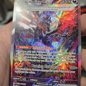 Puede incluir: Una carta coleccionable hologr&aacute;fica Charizard ex con 330 HP, que presenta el tipo Tera, la habilidad Infernal Reign y el ataque Burning Darkness. La tarjeta muestra ilustraciones vibrantes en papel de aluminio multicolor, texto detallado y el n&uacute;mero 234/091.