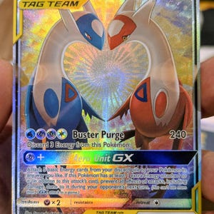 May include: A Latias & Latios GX Tag Team trading card with a holographic finish. The card features the two legendary Pokémon facing each other, forming a heart shape. Text includes Buster Purge, Aero Unit GX, 250 HP, and 170/181.
