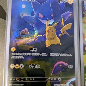 以下が含まれることがあります： ピカチュウとゲンガーが描かれたホログラフィックポケモンカード。カードには日本語のテキストとHP60が記載されています。背景には暗い森のシーンが描かれています。カードは保護スリーブに入っています。