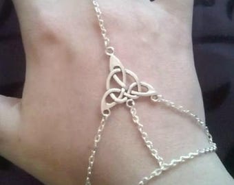 May include: A silver chain bracelet with a Celtic knot design. The bracelet is connected to a ring that can be worn on the finger.
