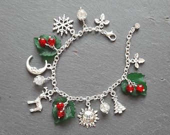 May include: A silver charm bracelet with a variety of charms, including a snowflake, a sun, a moon, a reindeer, a Christmas tree, and holly leaves with red berries.