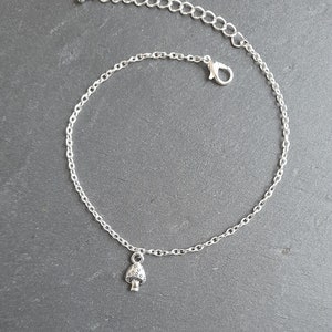 Puede incluir: Un tobillo de cadena de plata con un pequeño encanto de hongo. La cadena es delicada y tiene un cierre de langosta.