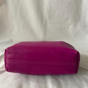 May include: A vibrant magenta leather tote bag with a stitched seam around the top edge.