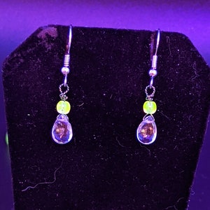 May include: A pair of silver dangle earrings with clear teardrop-shaped crystals and small yellow beads.
