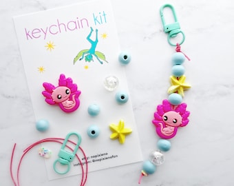May include: A pink axolotl keychain kit with blue and yellow beads, a star charm, and a turquoise clasp. The kit includes everything you need to make your own axolotl keychain.