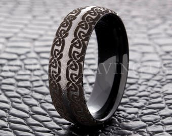 May include: A black tungsten carbide ring with a Celtic knot design engraved on the band. The ring has a brushed finish and a polished inner band.