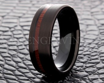 May include: A black tungsten carbide ring with a brown wood inlay. The ring has a brushed finish and a beveled edge.