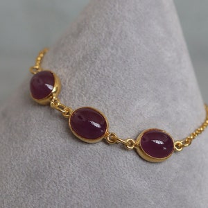 Peut inclure: Un bracelet en chaîne dorée avec trois pierres précieuses ovales de couleur violette.