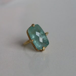 May include: A gold ring featuring a large, rectangular, light blue gemstone.
