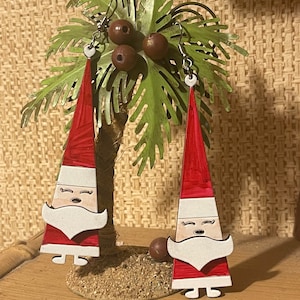 May include: A pair of red and white Santa Claus earrings. The earrings are made of wood and have a whimsical design.