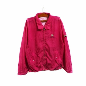 Puede incluir: Una chaqueta cortavientos rosa con cierre de cremallera y un logotipo que dice "Simpson" en la parte delantera. La chaqueta tiene un pequeño parche en la manga izquierda.