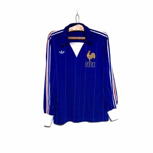 May include: A blue and white striped long-sleeved football shirt with red and white stripes on the sleeves. The shirt has the Adidas logo on the left chest and a rooster with "FFF" embroidered on the right chest.