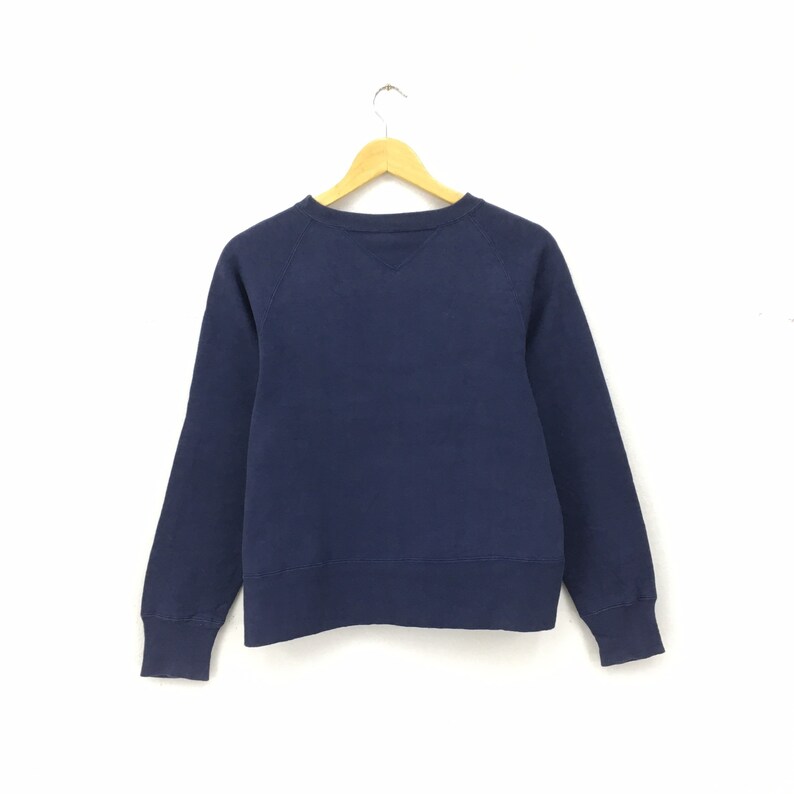 May include: A navy blue sweatshirt with long sleeves and a crew neck.