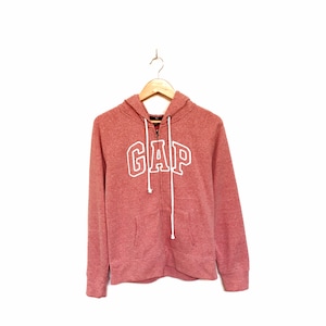 Puede incluir: Una sudadera con capucha rosa con un logotipo "GAP" blanco en la parte delantera. La sudadera tiene una cremallera y una capucha con cordón.