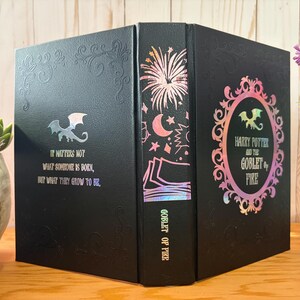 May include: Black book with iridescent accents and the text "Harry Potter and the Goblet of Fire." The book features a dragon emblem and the quote "It matters not what someone is born, but what they grow to be."
