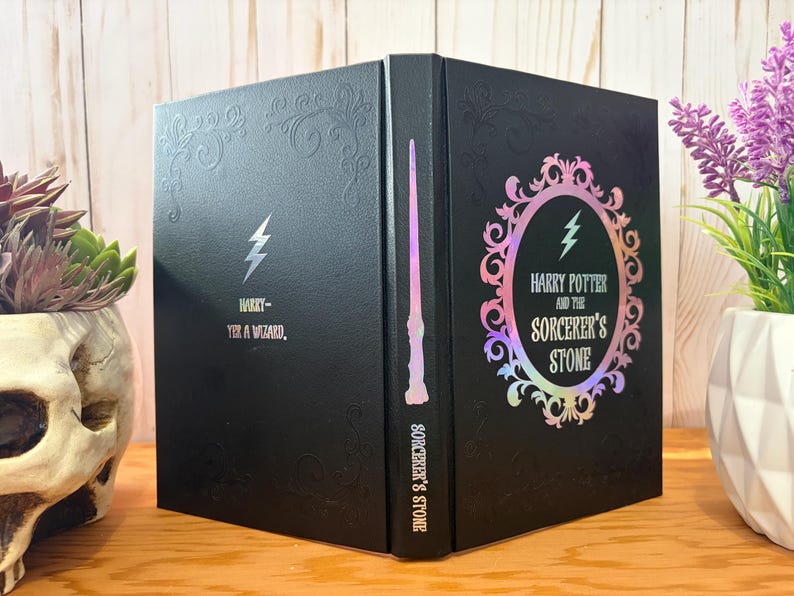 May include: Black book with embossed floral design and the text "Harry - Yes, a Wizard." The book features a lightning bolt and a holographic oval with the text "Harry Potter and the Sorcerer's Stone."