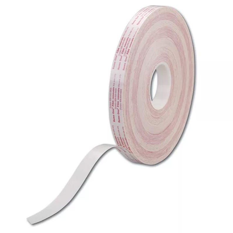 Op de afbeelding: Een rol witte dubbelzijdige tape met een rood label waarop "Scotch" en "Clear Film" staat.