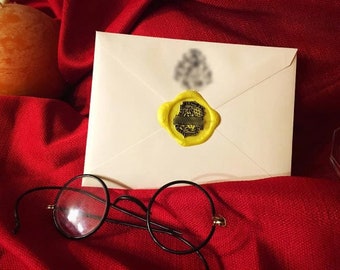 May include: A white envelope sealed with a yellow wax stamp, resting on a red fabric. Black-framed round glasses are in the foreground. A candle is visible in the background. The wax seal has a blurred design.