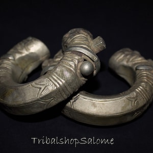 Könnte beinhalten: Zwei silberne Armreifen mit aufwendigen Designs und einer strukturierten Oberfläche. Die Armreifen sind aus Metall und haben ein traditionelles Aussehen.