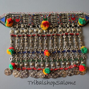 Könnte beinhalten: Eine silberne Halskette mit bunten Perlen und Bommeln. Die Halskette hat ein breites Band mit aufwendigen Designs und eine Reihe von Münzen am unteren Ende. Der Text "TribalshopSalome" ist am unteren Rand des Bildes sichtbar.