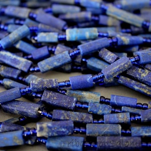 May include: A strand of blue lapis lazuli beads with gold flecks, separated by dark blue glass beads.
