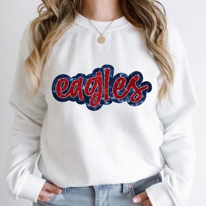 May include: White sweatshirt with a red and blue sequined "Eagles" design.