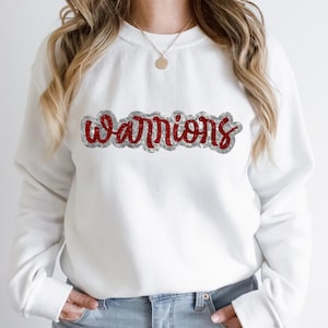 May include: White sweatshirt with a red and silver glitter design that says "warriors".