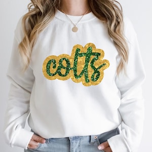 May include: White sweatshirt with a green and gold sequined "Colts" design.