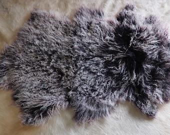 Op de afbeelding: Een pluche schapenvachtkleed met een donkergrijs en wit kleurpatroon. Het kleed is zacht en pluche en zou perfect zijn om elke kamer een vleugje warmte en comfort te geven.