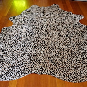 Op de afbeelding: Een wit en bruin koeienhuidkleed met een luipaardprint.