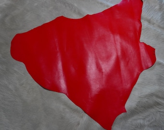 May include: A bright red piece of leather with a smooth, shiny finish. The leather is laid out flat on a white surface.