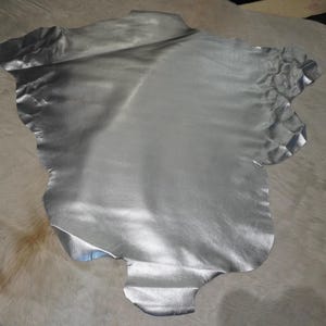 May include: A silver leather hide with a smooth, shiny finish. The hide is irregularly shaped and has a slightly wrinkled texture.