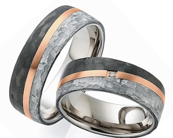 May include: Two rings featuring a dark gray carbon fiber band with a woven texture, a central rose gold inlay, and a smooth dark gray edge. One ring includes a single small round clear gemstone set into the rose gold band.