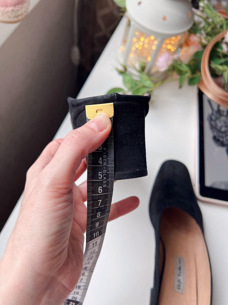 May include: Black suede shoe with a square toe. A measuring tape shows the heel height is approximately 7.6 cm. The shoe is on a white surface.
