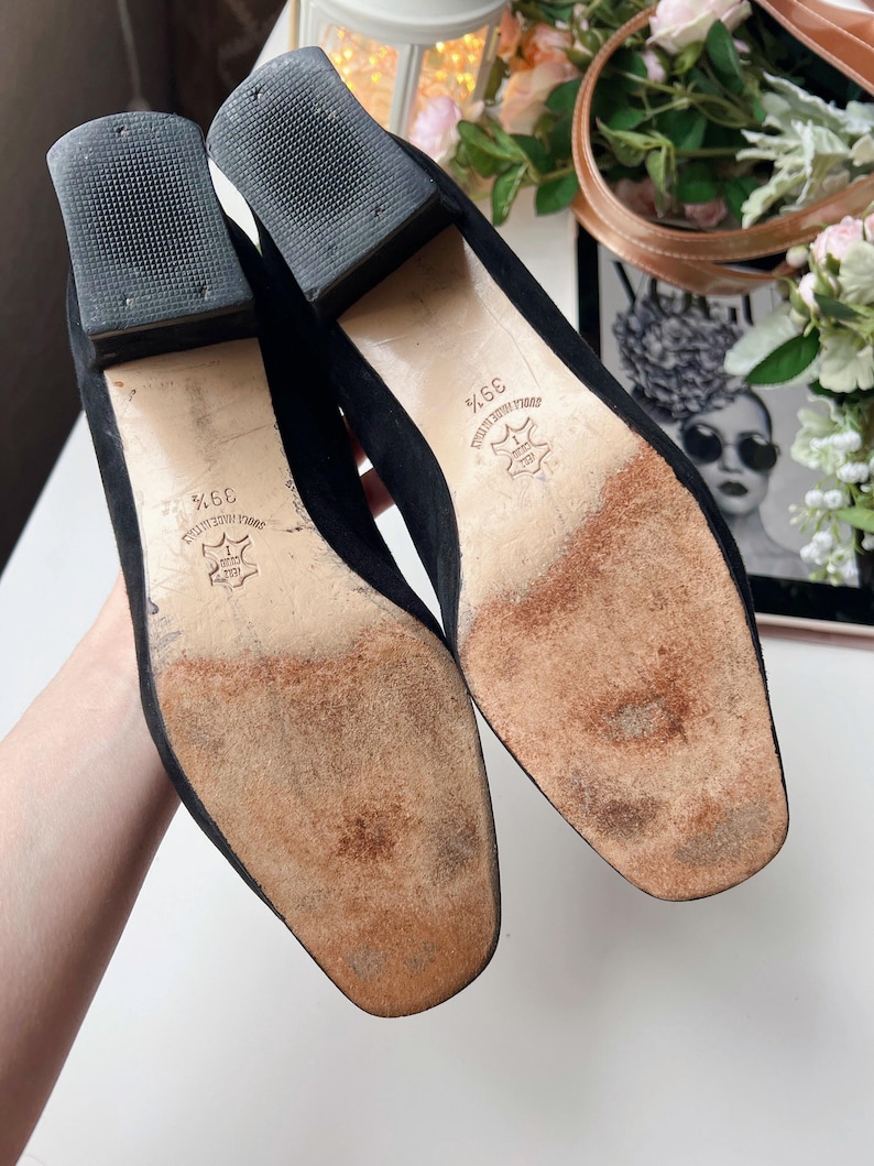 May include: A pair of black suede heeled shoes, size 39, with square toes and block heels. The soles show wear and the heels have a textured rubber base. The shoes are likely vintage or pre-owned.