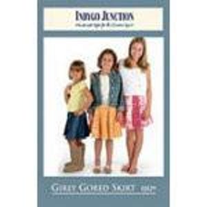 May include: Three girls wearing skirts and tops. The girl on the left wears a denim skirt and a yellow top, the middle girl wears an orange skirt and a denim jacket, and the girl on the right wears a pink skirt and a white top. The text "Indigo Junction" is at the top.